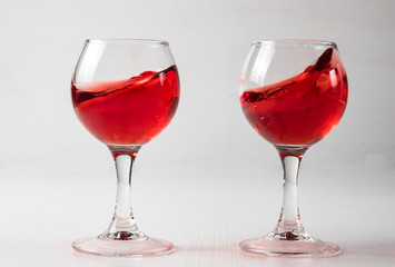 Two glasses with red juice, wine with different splashes