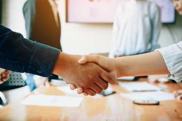 Team of entrepreneurs collaborating deal shaking hands in a modern office.