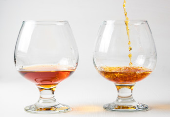 Two glasses for cognac with whiskey with different splashes