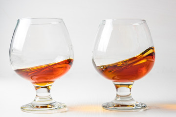 Two glasses for cognac with whiskey with different splashes