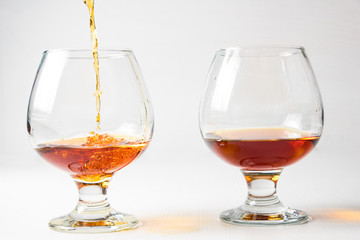 Two glasses for cognac with whiskey with different splashes