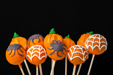 concept of Halloween party with glazed cake pops on black background