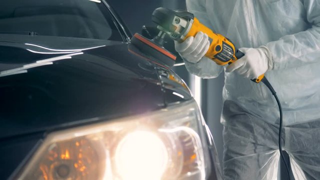 One man in uniform holds a special disk while polishing a car. 4K.