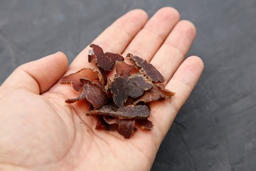 A hand holding biltong (beef jerky). This is a traditional food snack in South Africa. 