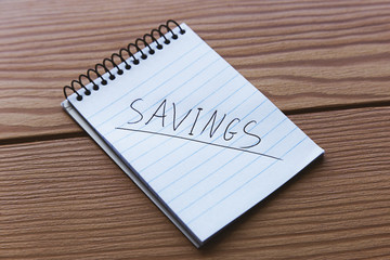 A notepad with the word, "SAVINGS" written on it.  Saving concept image. 