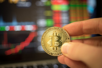 Holding Bitcoin the digital currency in front of a trading screen cryptocurrency 