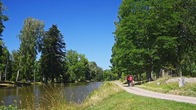 Two persons cycling along the Gota canal on a gravel country road in summer. Location outside Jonsboda in Sweden.