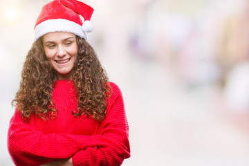 Young brunette girl wearing christmas hat over isolated background happy face smiling with crossed arms looking at the camera. Positive person.