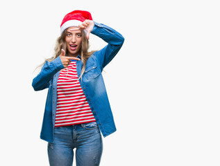 Beautiful young blonde woman wearing christmas hat over isolated background smiling making frame with hands and fingers with happy face. Creativity and photography concept.