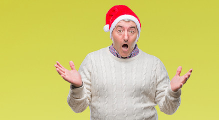 Fototapeta premium Handsome senior man wearing christmas hat over isolated background celebrating crazy and amazed for success with arms raised and open eyes screaming excited. Winner concept