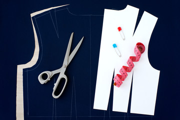 Cut fabric in the process of sewing clothes. Sew clothes on paper pattern. View from above. Sewing a dress made of blue fabric. Tape measure, tailoring scissors and fabric for sewing.