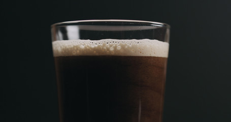 Closeup dark stout beer with bubbles over black background