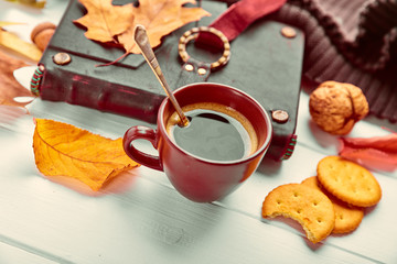 Cup coffee with book in leather binding autumn dry leaf and warm