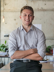 Successful young business man start up, crossed arm and smiling in workplace.