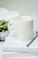 White cup and spoon on white books