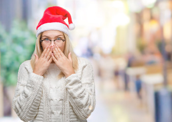 Young caucasian woman wearing christmas hat over isolated background shocked covering mouth with hands for mistake. Secret concept.