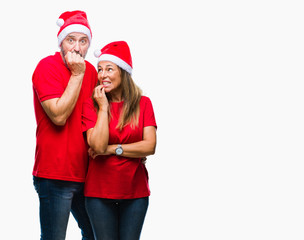 Middle age hispanic couple wearing christmas hat over isolated background looking stressed and nervous with hands on mouth biting nails. Anxiety problem.