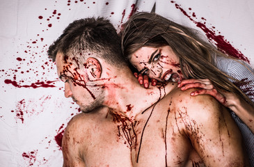 Sexy Vampire Coule with dripping blood on her mouth on bloody background. Sexy woman vampire bites...