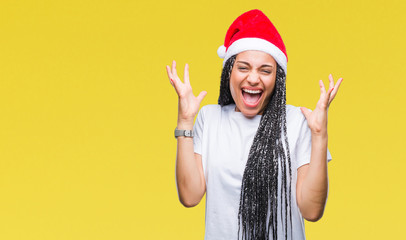 Young braided hair african american girl wearing christmas hat over isolated background celebrating...