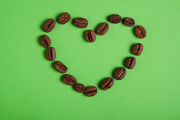 close up heart shaped coffee beans on green background top view, valentine day concept