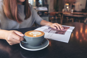 Closeup image of a beautiful asian woman reading magazine while drinking coffee in modern cafe