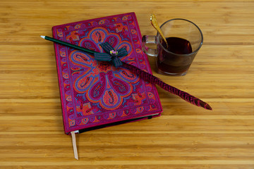 Hand writing books wallet and notebook placed on a wooden table. top view image of open notebook with blank pages next to cup of coffee on wooden table. Notepad with pencil on the wood background.