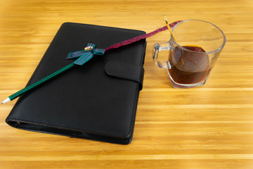 Hand writing books wallet and notebook placed on a wooden table. top view image of open notebook with blank pages next to cup of coffee on wooden table. Notepad with pencil on the wood background.