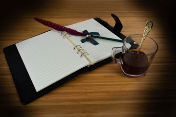 Hand writing books wallet and notebook placed on a wooden table. top view image of open notebook with blank pages next to cup of coffee on wooden table. Notepad with pencil on the wood background.