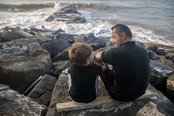 father and son are talking on the beach © Birol