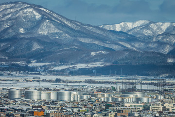 view of city; chemical tank plant and snow mountains in the winter