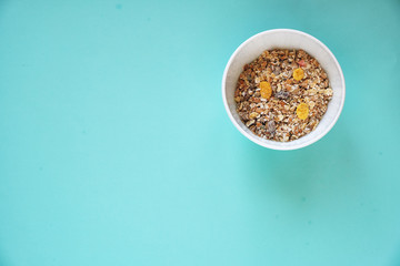 muesli in white bowl on blue background top view with copy space for text, healthy food concept 