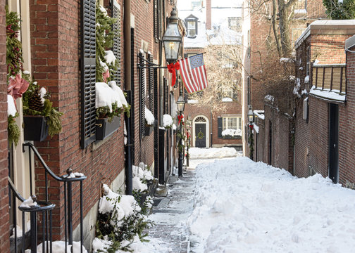 USA, Boston - January 2018 - Acorn Street in the snow with the American flag flying