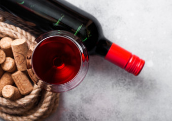 Elegant glass and bottle of red wine with corks on stone kitchen table background. Top view