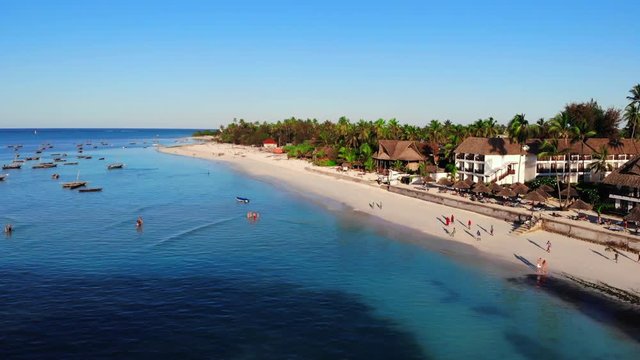 Fantastic aerial panorama of paradise. Beautiful tropical island with small houses on the sand and long coastal beach full of . 4K (UHD).