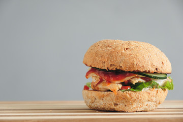 Homemade burger with fried chicken on wood table with copy space on gray background. Fastfood concept