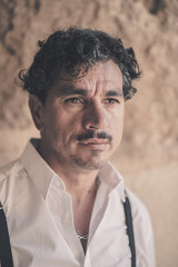 Portrait of a man with an interesting face typical of southern Italy, that can be defined both handsome or ugly, with black hair, moustaches, white skirt.