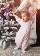 Merry Christmas and Happy New Year family, child, childhood and parenthood concept - happy little baby learning to walk with mother help at home