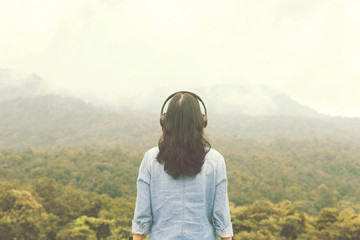 Women with headphones back view. looks into the distance with nature in the horizon.Amidst the beautiful nature.