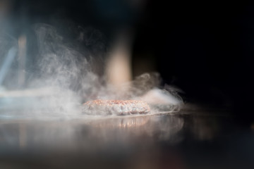 Hamburger cutlet frying on pan.Natural meet loaf pieces cooking in the kitchen.Burger sandwich meat being cooked with a lot of white smoke from a fat and oil.