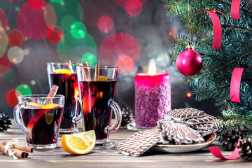Christmas mulled wine and cookies on wooden table decorated fir branches with red ball and candle.