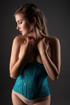 Slim blonde in corset in the dark profile view