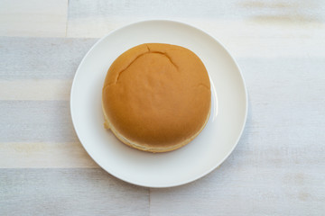 Burger roll on a plate, wooden background and copy space