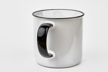Clean enamel mug with black handle. White tin cup for branding isolated on white background. Realistic enamel metal white mug.