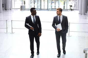 Two multinational young businessmen discussing business at meeting in office.