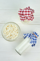 Dairy products on white background. Top view on glass bottles with milk, yogurt and bowl of fresh cottage cheese. Healthy food concept.