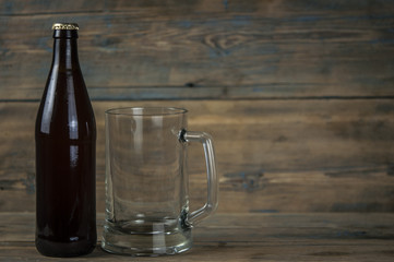 Empty beer bottle and glass on grunge wooden background