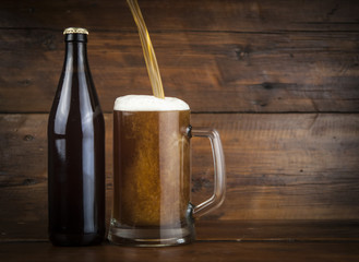 bottle and glass with beer on wood table