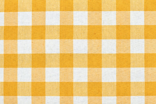 White and yellow checkered tablecloth background. Yellow gingham tablecloth background or texture. Plaid design picnic cloth.
