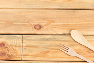 Wooden fork and spoon with copy space. Natural wooden cutlery on light wooden boards with text space. Handmade kitchen utensils.