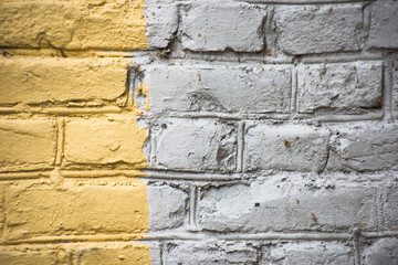 Uneven white brick wall painted with yellow paint